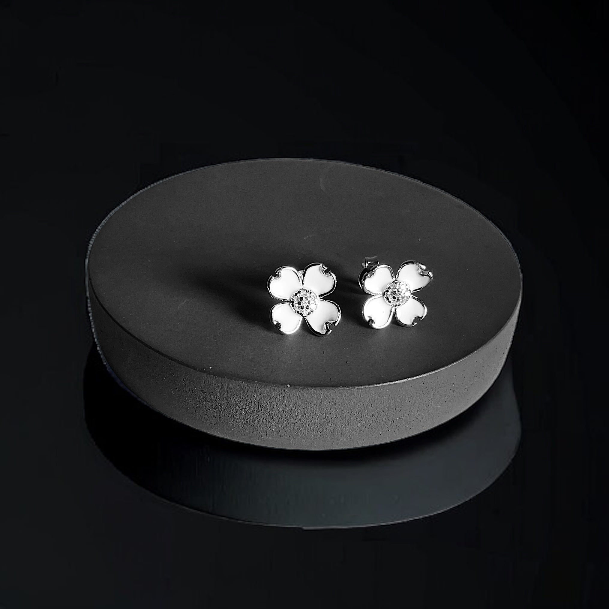 a pair of white flower earrings sitting on a black surface