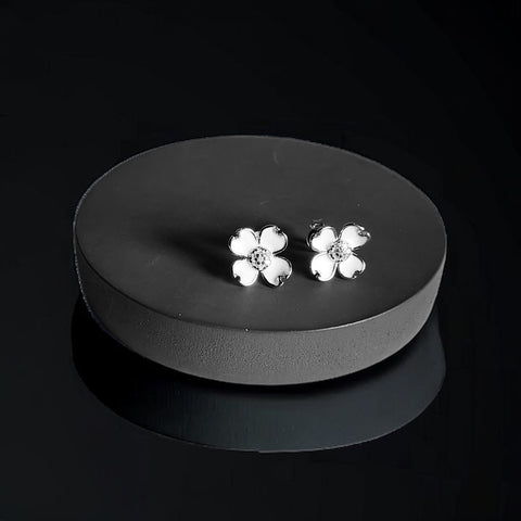 a pair of white flower earrings sitting on a black surface