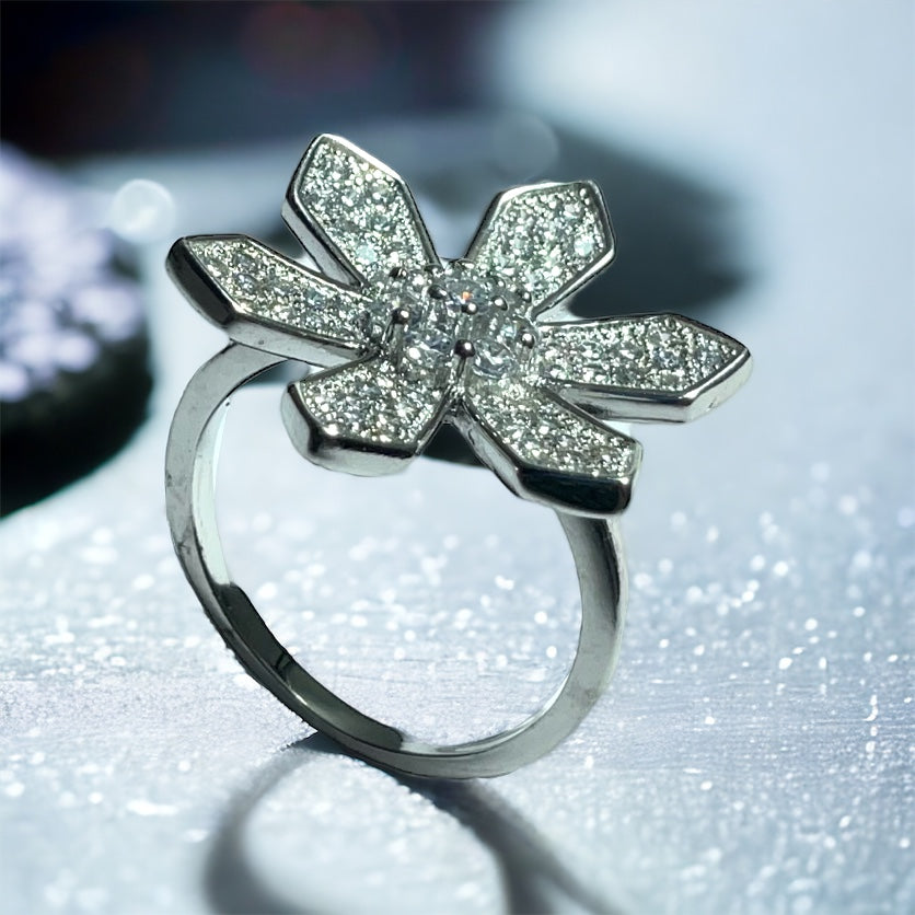 a diamond flower ring sitting on top of a table