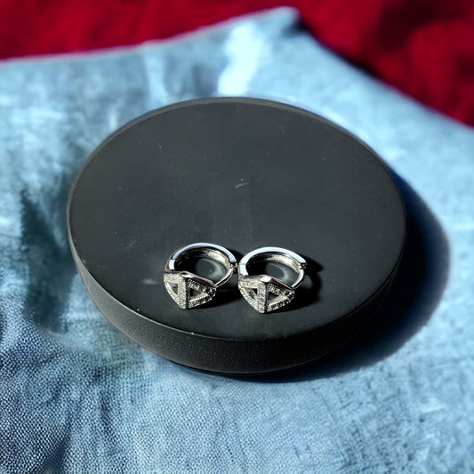 a pair of silver earrings sitting on top of a black box