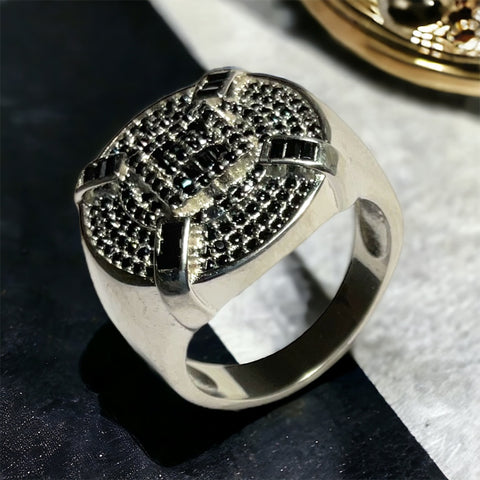 a silver ring with black diamonds on a table