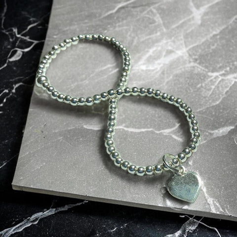 a silver beaded bracelet with a heart charm