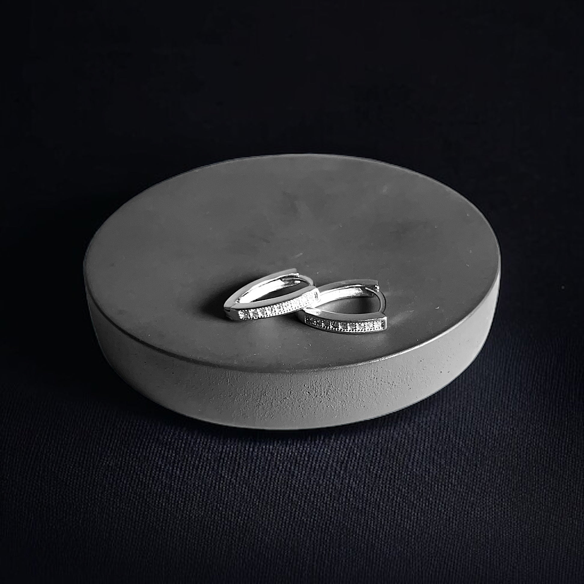 a couple of silver rings sitting on top of a round box