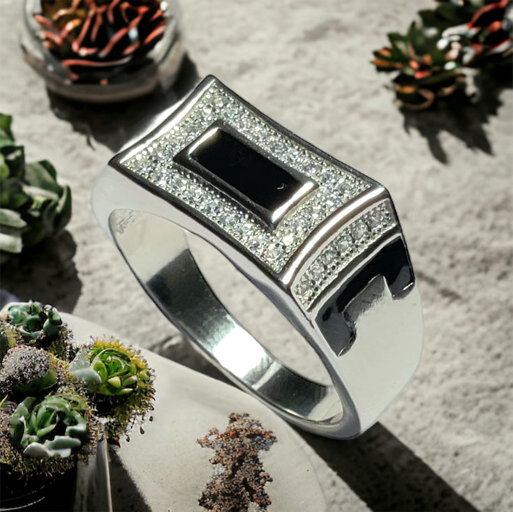 a silver ring with a black stone surrounded by succulents