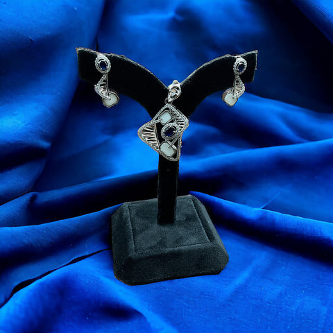a pair of earrings is on a black stand