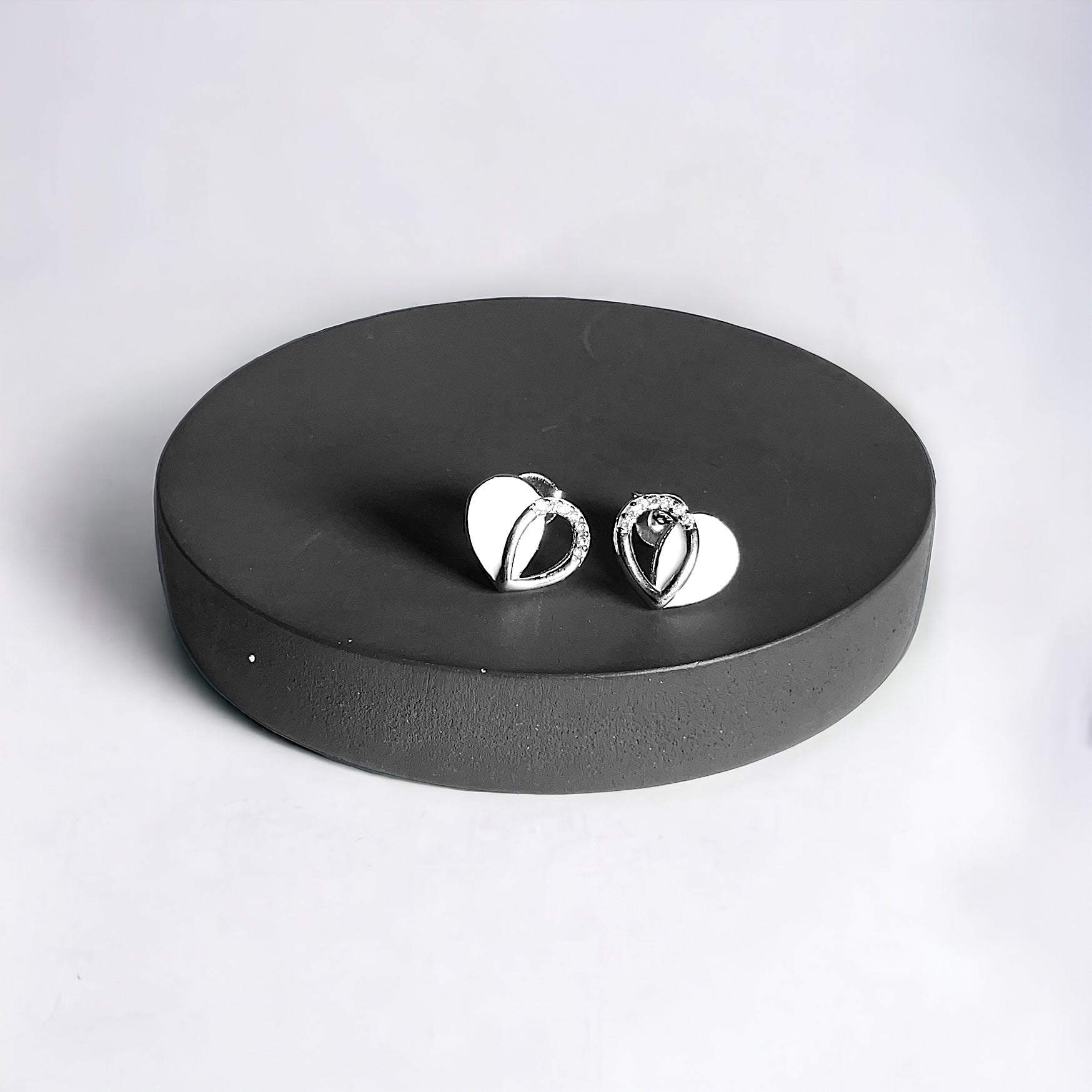 a pair of silver earrings sitting on top of a black plate
