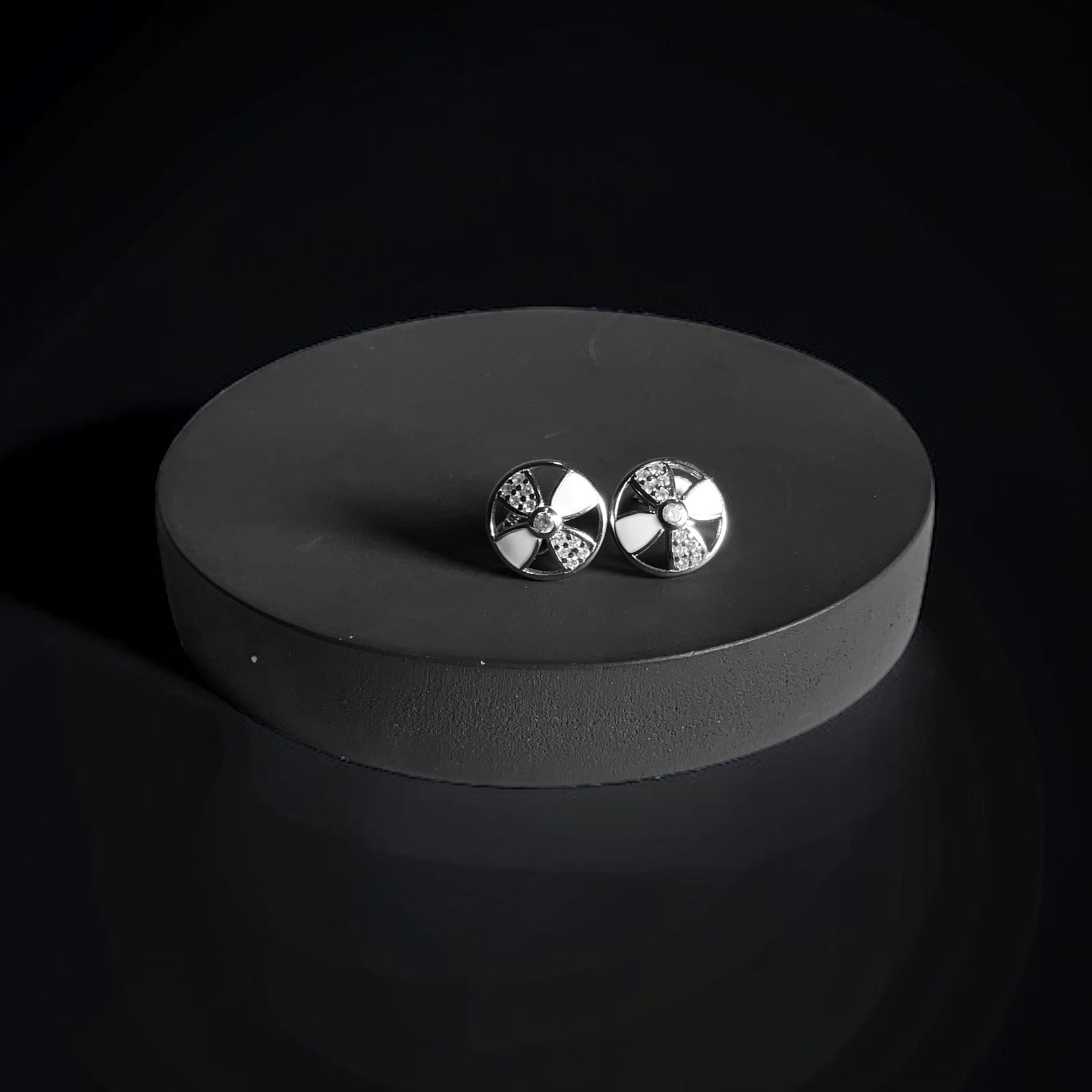 a pair of earrings sitting on top of a black surface