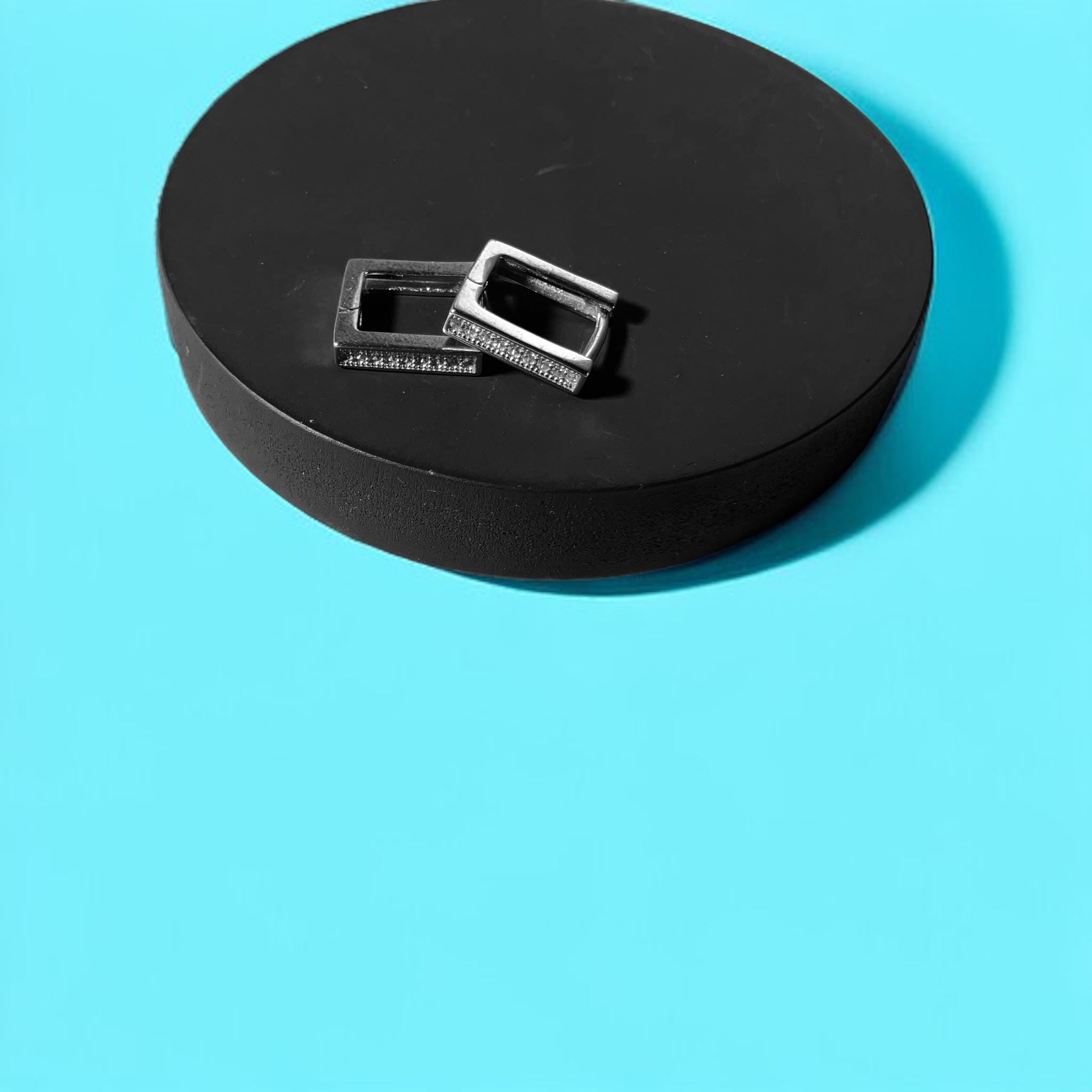 a black object with a metal buckle on a blue background