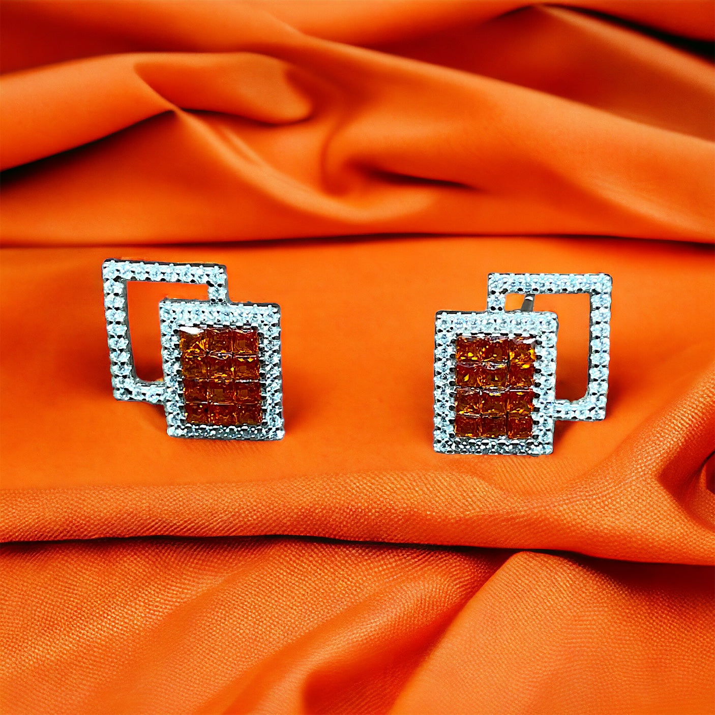 a close up of a pair of earrings on an orange cloth