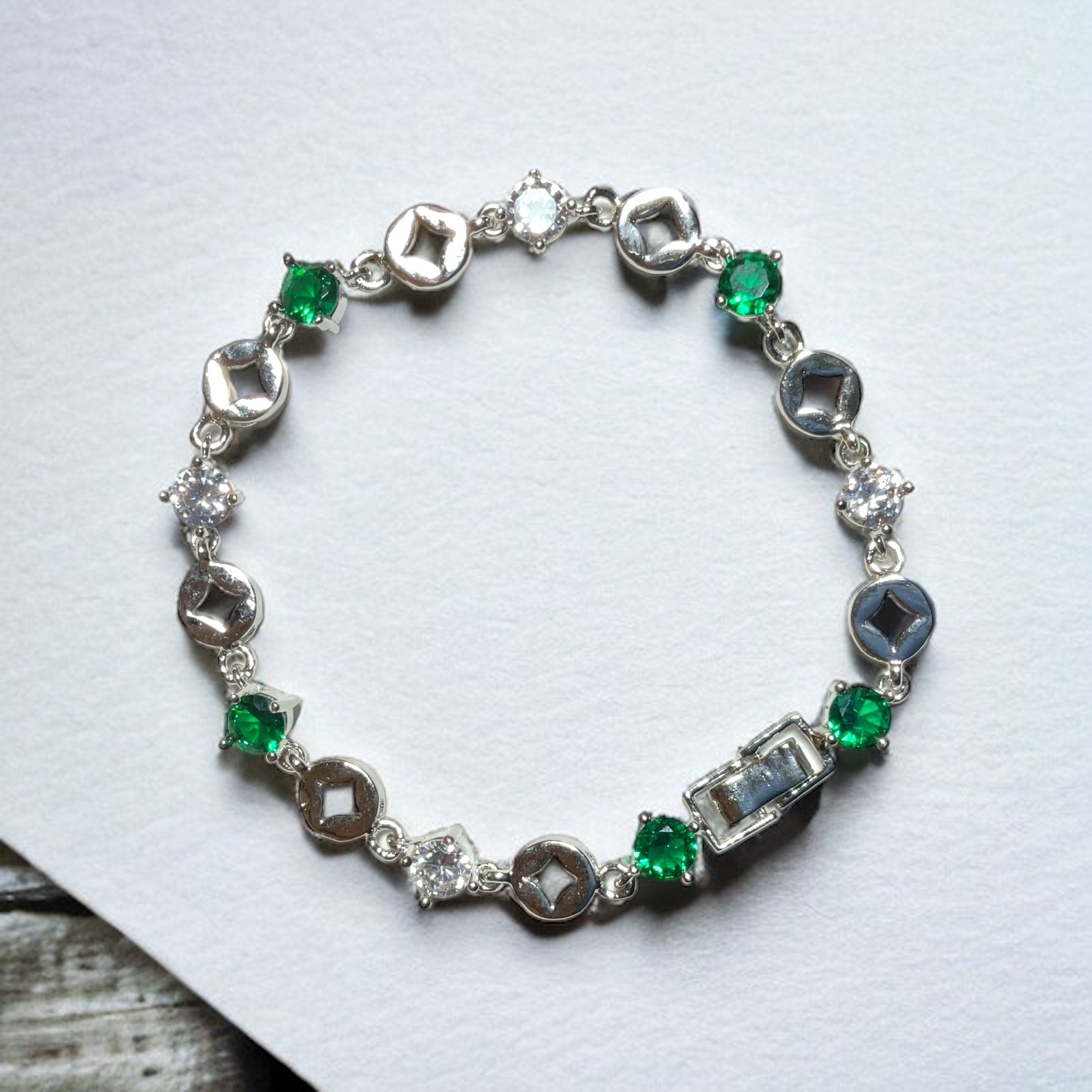 a silver bracelet with green and white stones