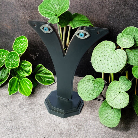 a green plant with blue eyes is next to a black sculpture