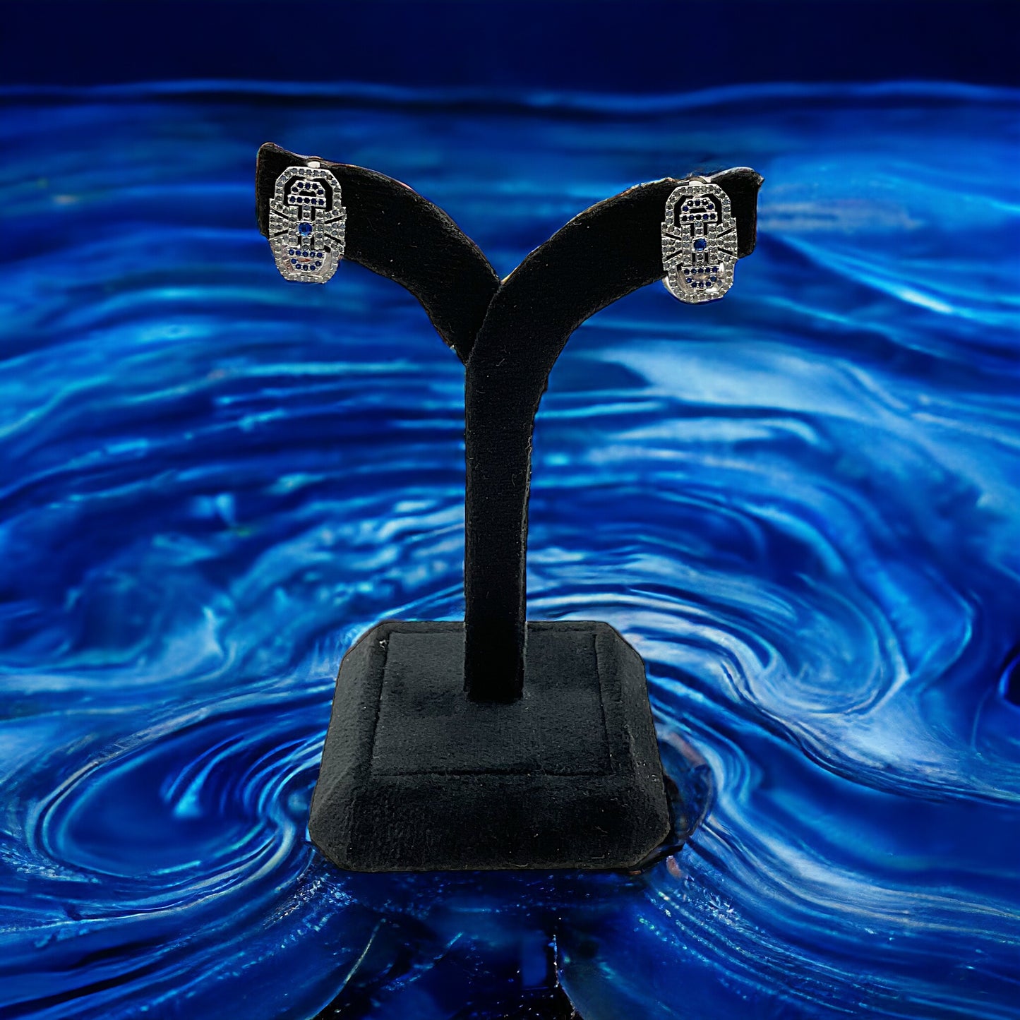 a pair of earrings sitting on top of a black stand