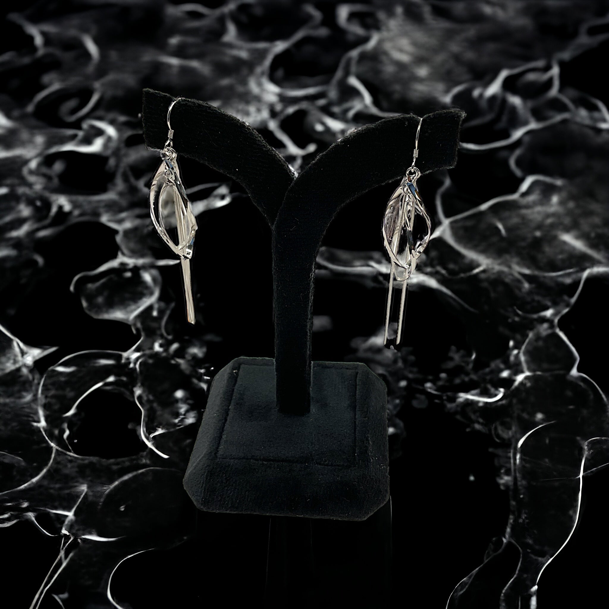 a pair of silver earrings on a black stand