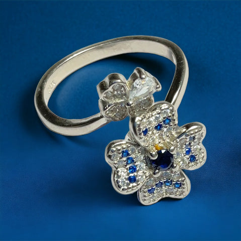 a diamond and sapphire flower ring on a blue background