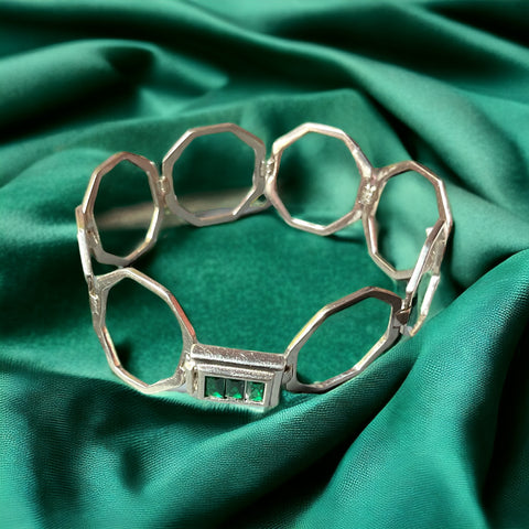 a close up of a metal bracelet on a green cloth
