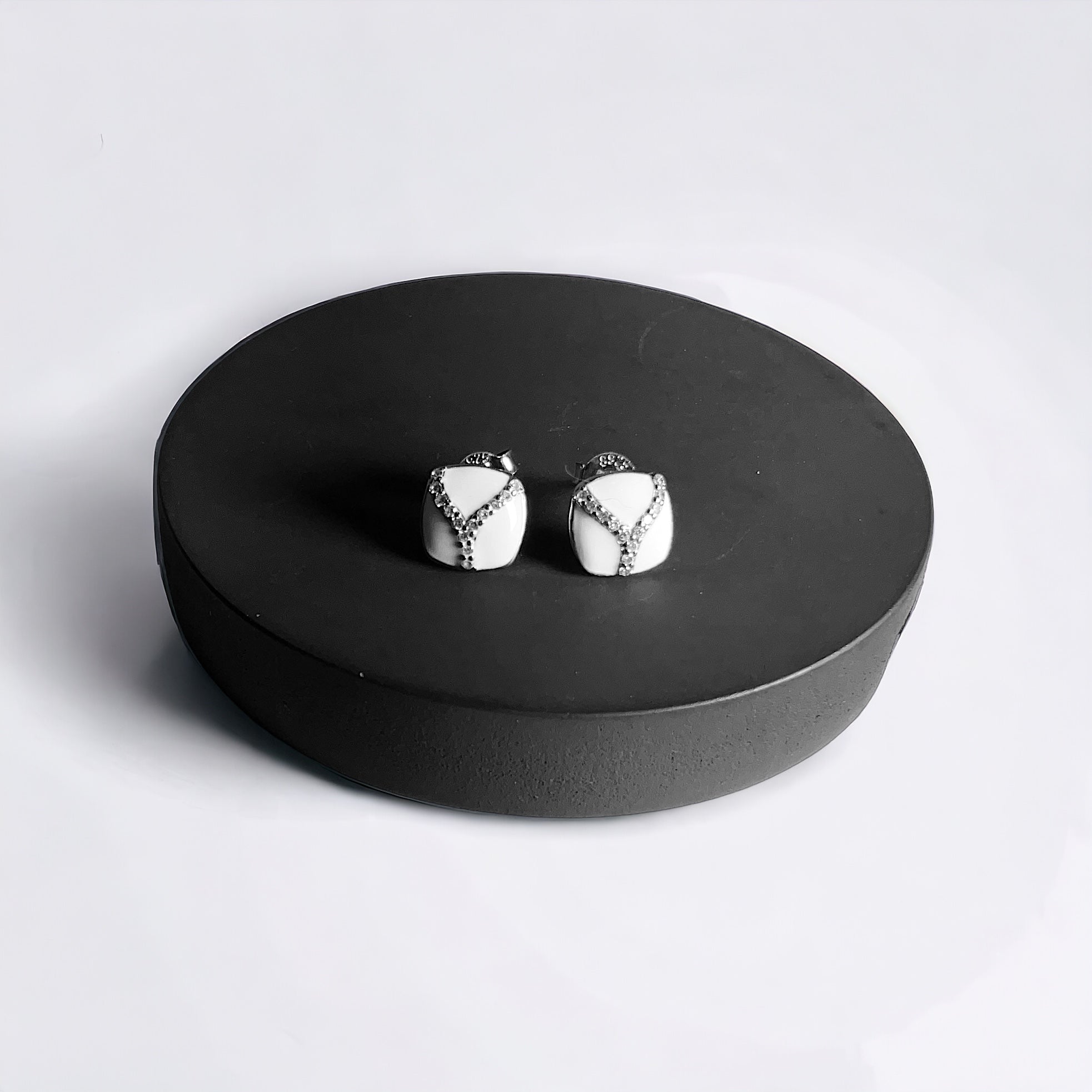 a pair of earrings sitting on top of a black plate