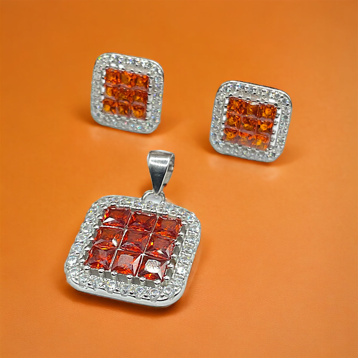 a set of three square shaped orange and white diamond pendants