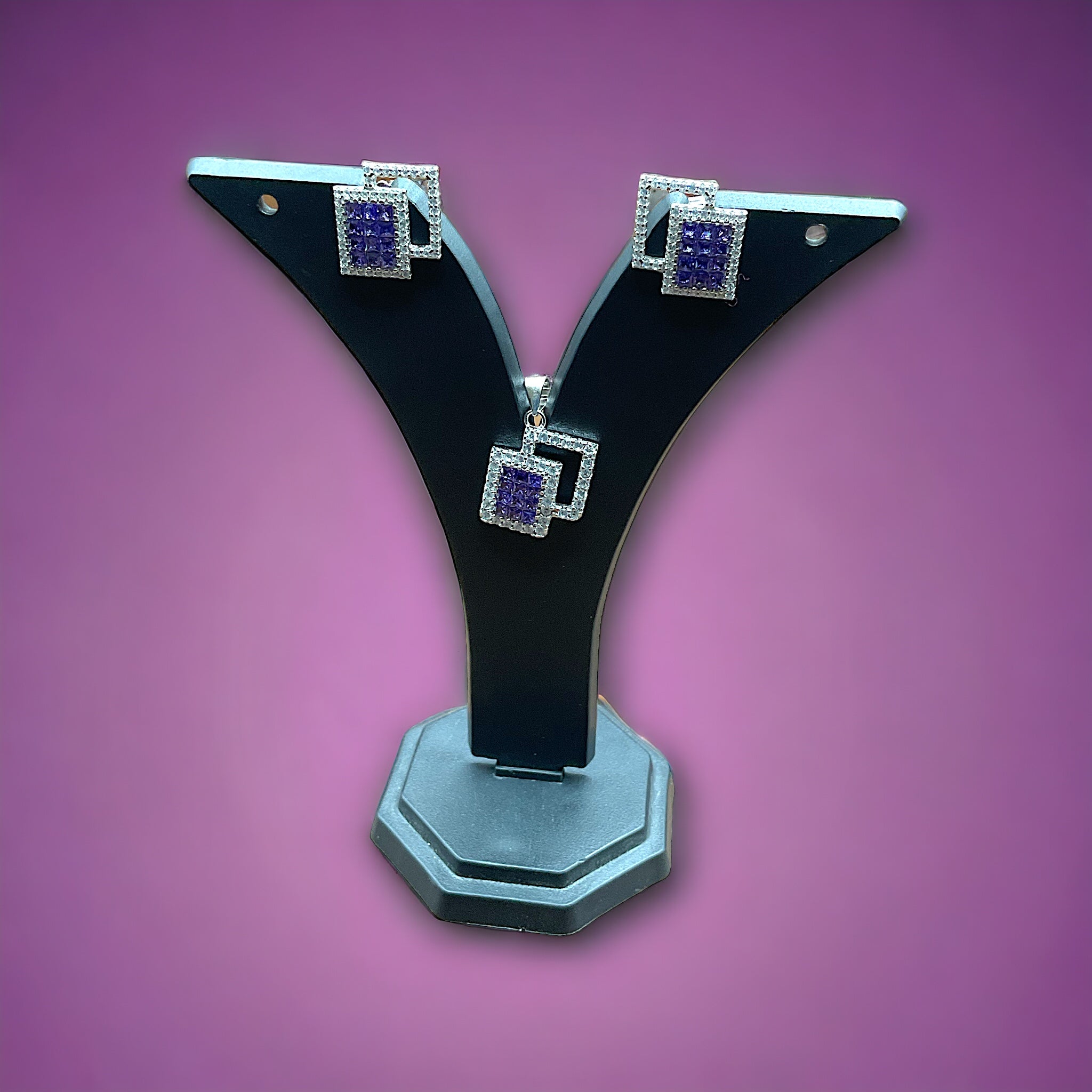 a pair of black and silver earrings on a purple background