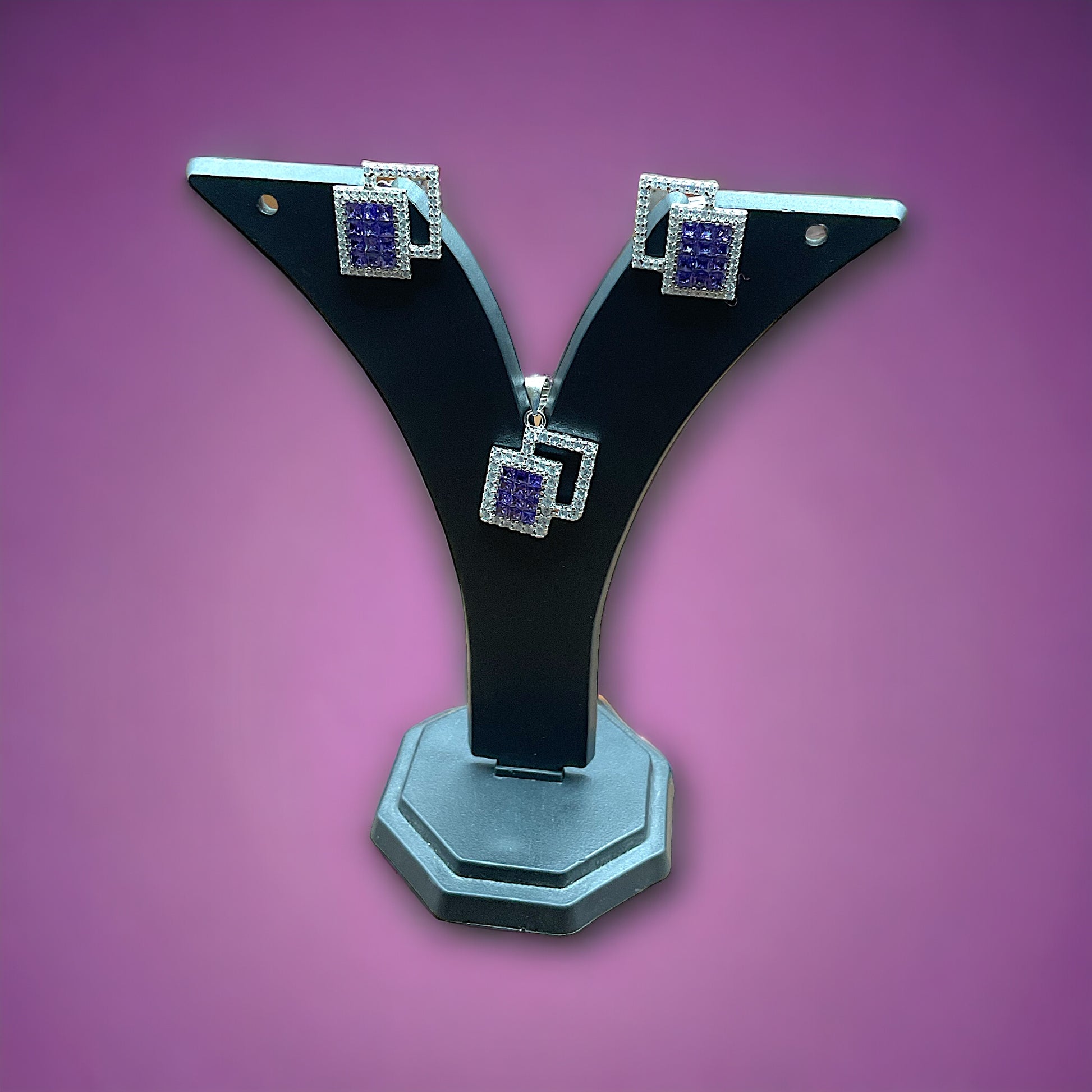 a pair of black and silver earrings on a purple background