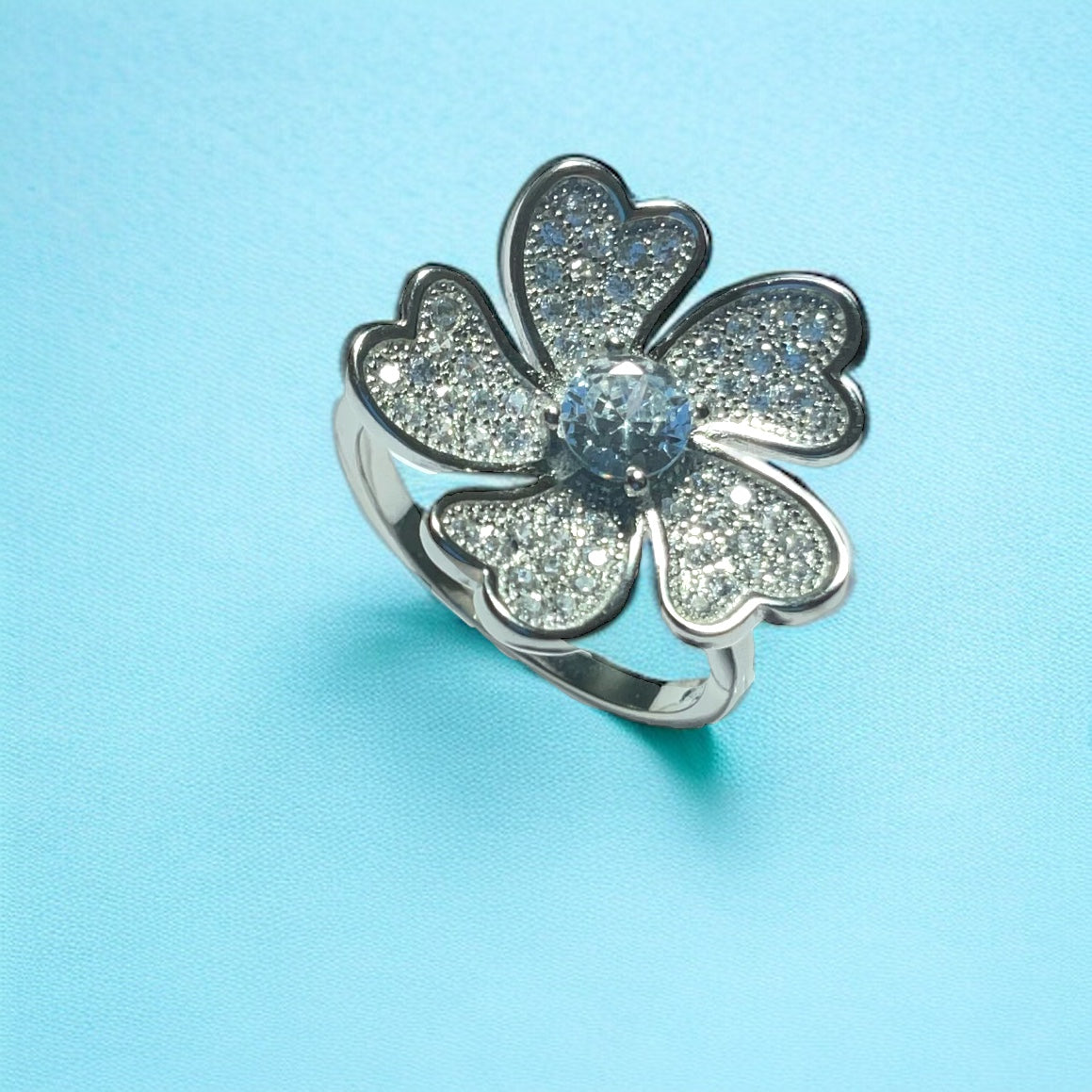 a silver ring with a flower design on a blue background