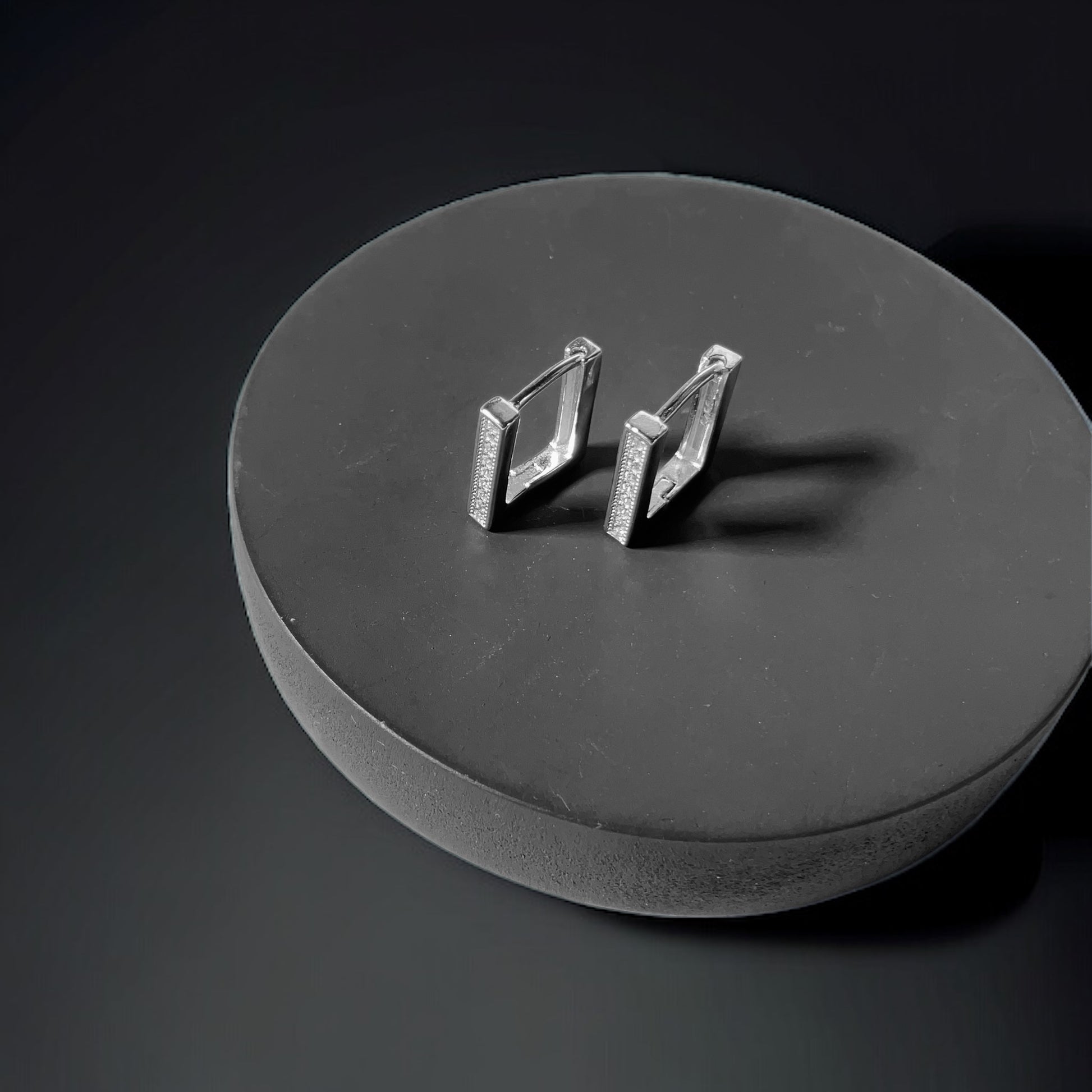 a pair of earrings sitting on top of a black surface