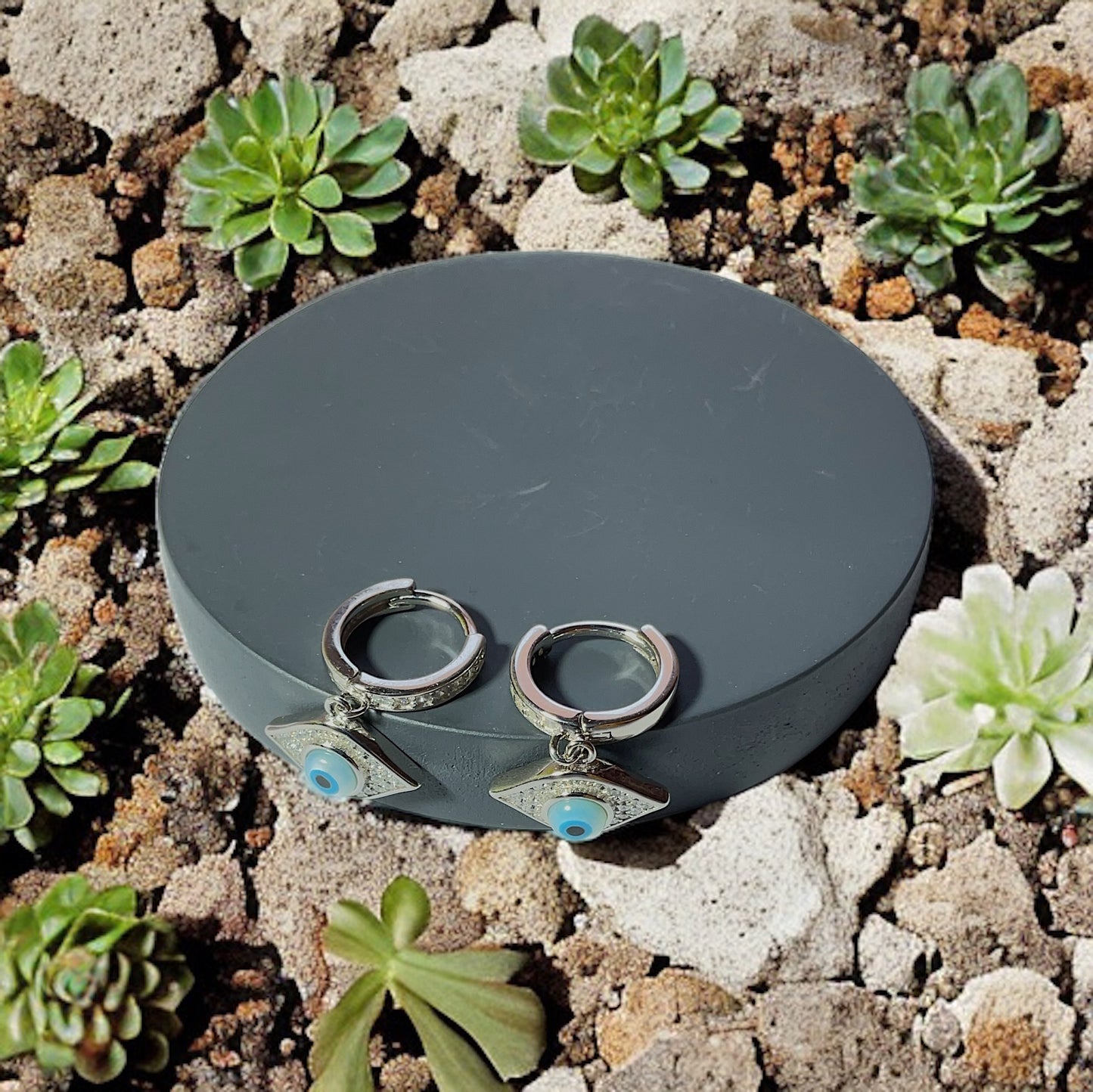 a pair of silver earrings sitting on top of a rock