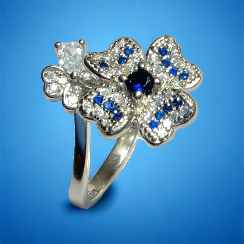 a diamond and sapphire flower ring on a blue background