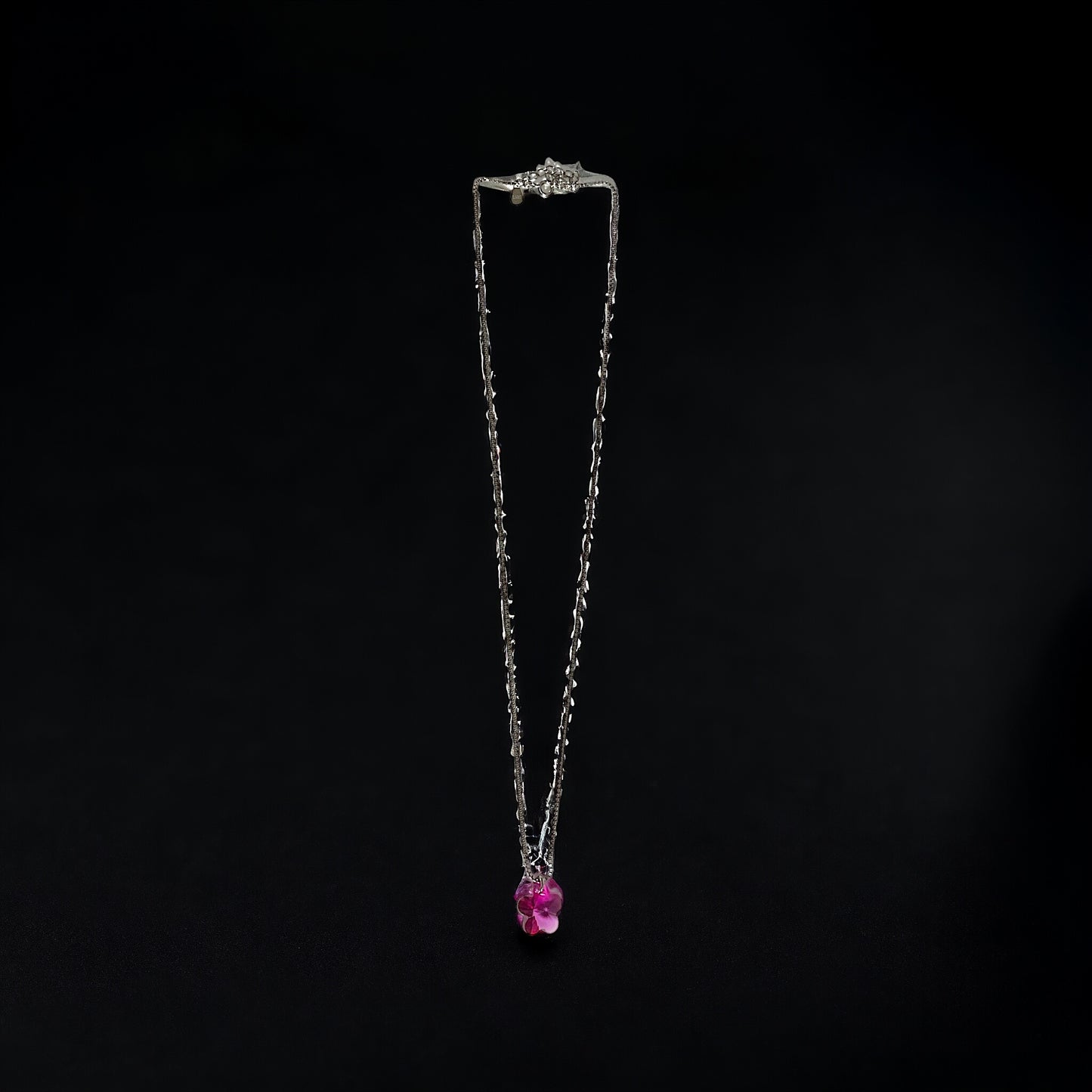 a necklace with a pink stone hanging from it