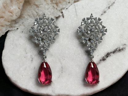 a pair of pink and white earrings on a marble slab