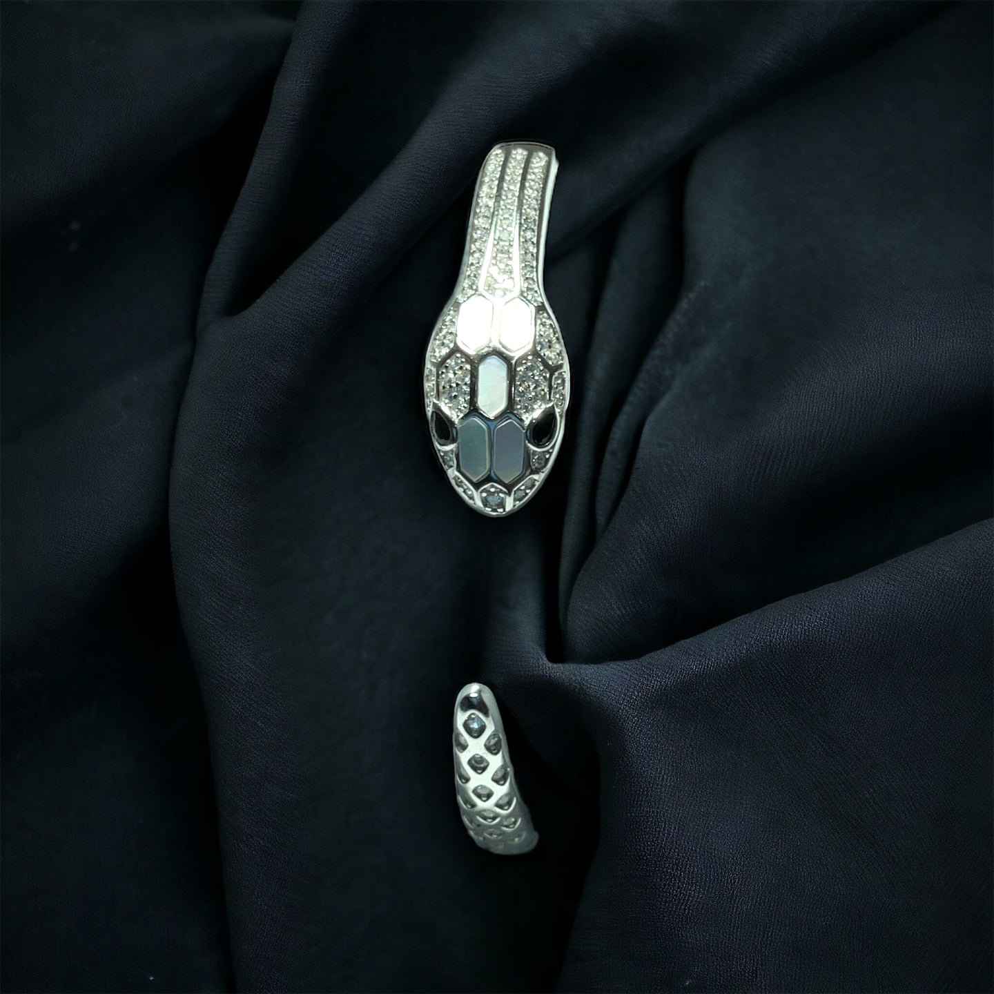 a silver brooch and a pair of shoes on a black cloth