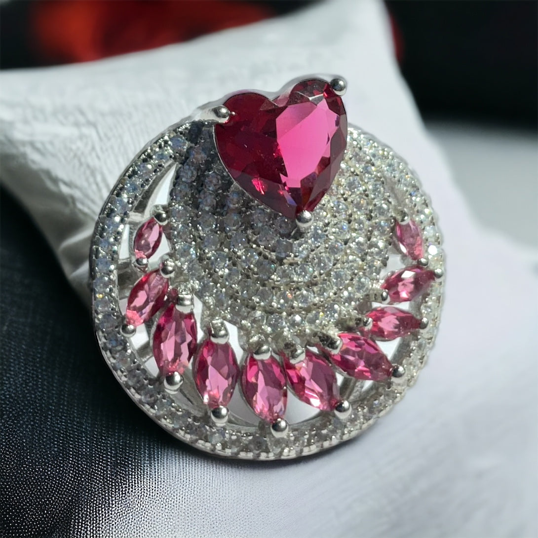 a ring with a heart surrounded by pink stones