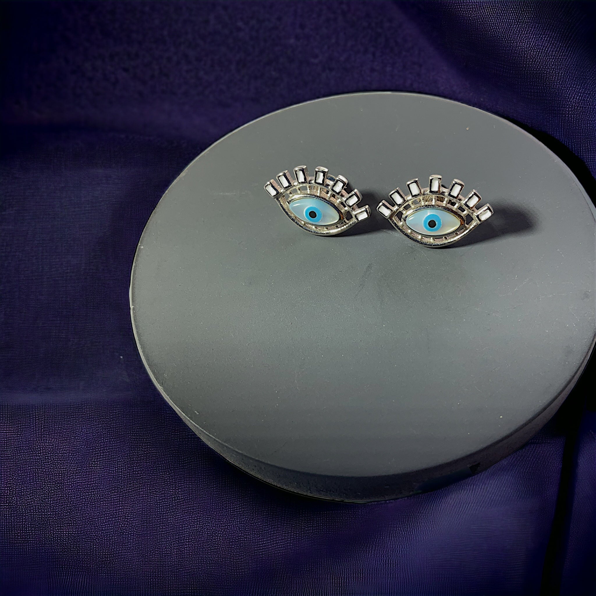 a pair of earrings with blue eyes on a silver plate