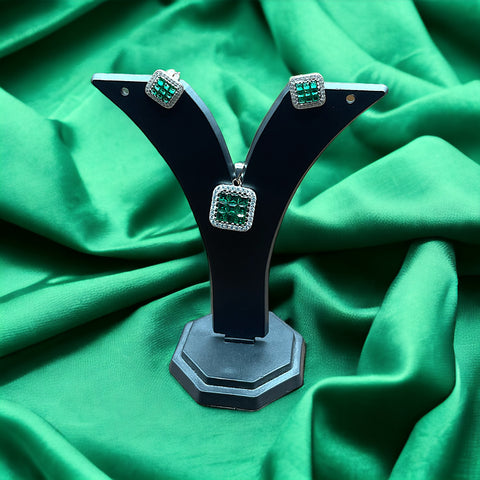 a pair of earrings on a stand on a green cloth
