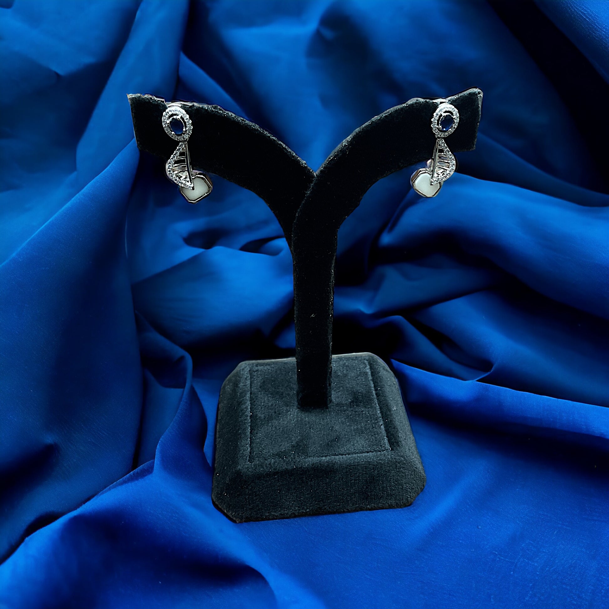 a pair of earrings on a black stand