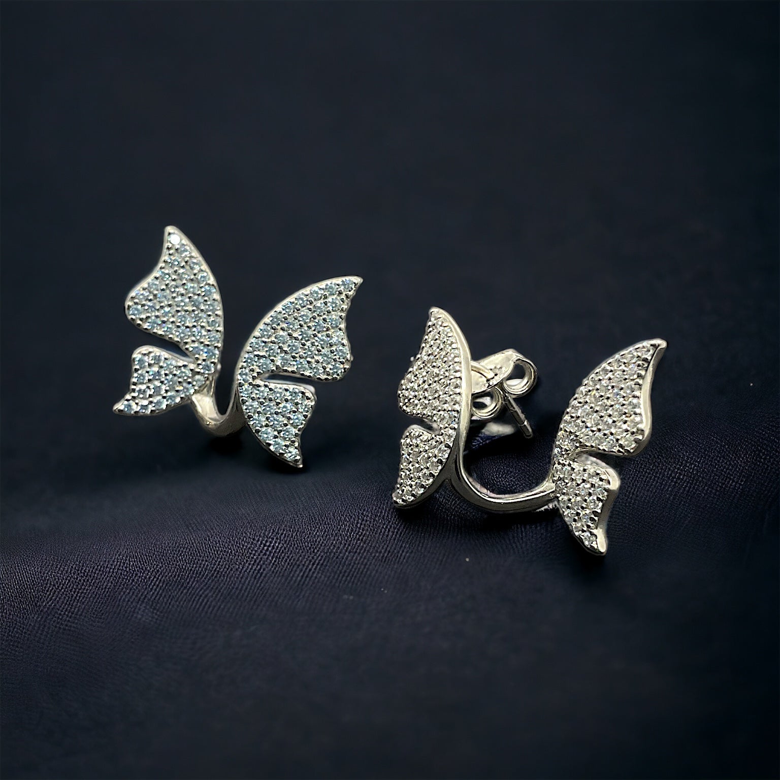 a pair of butterfly shaped earrings on a black background