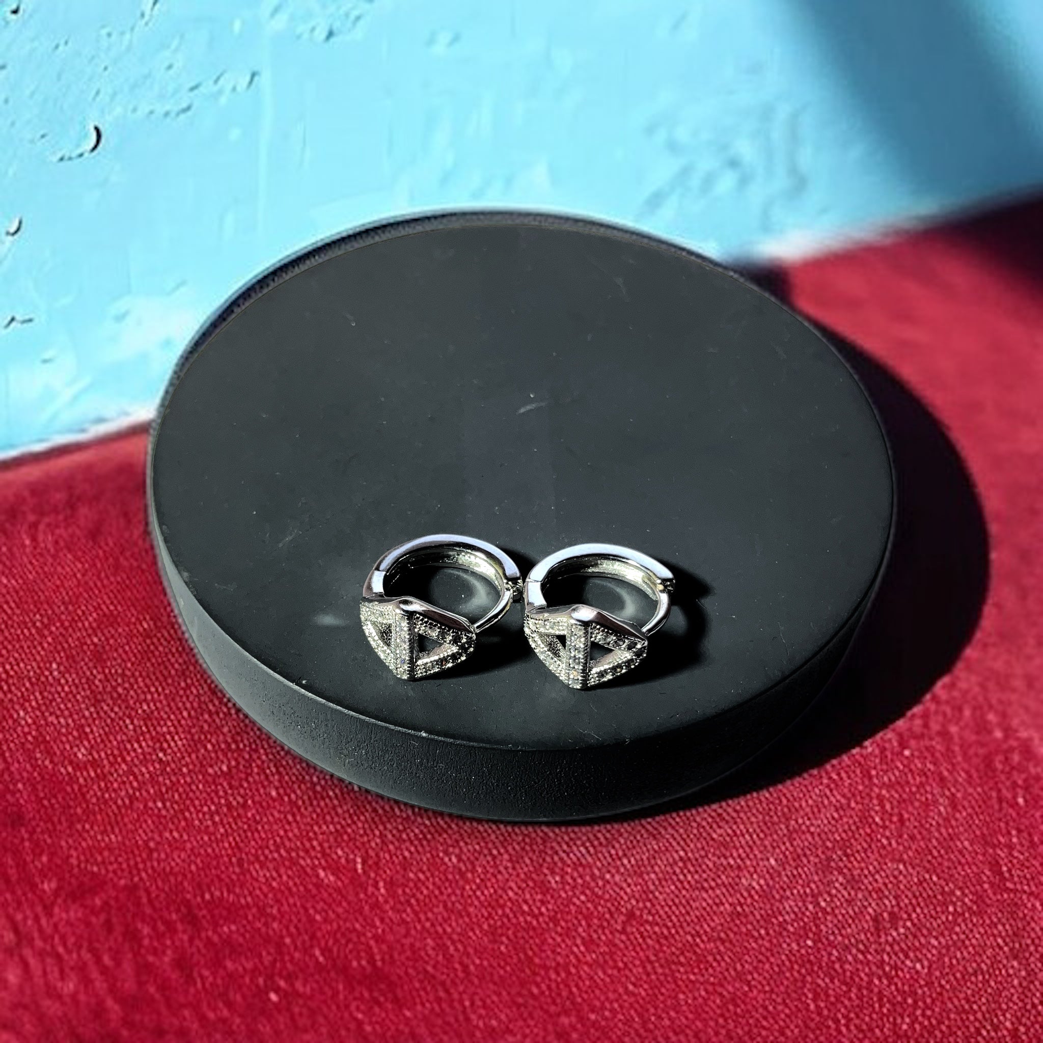 a pair of silver earrings sitting on top of a black box