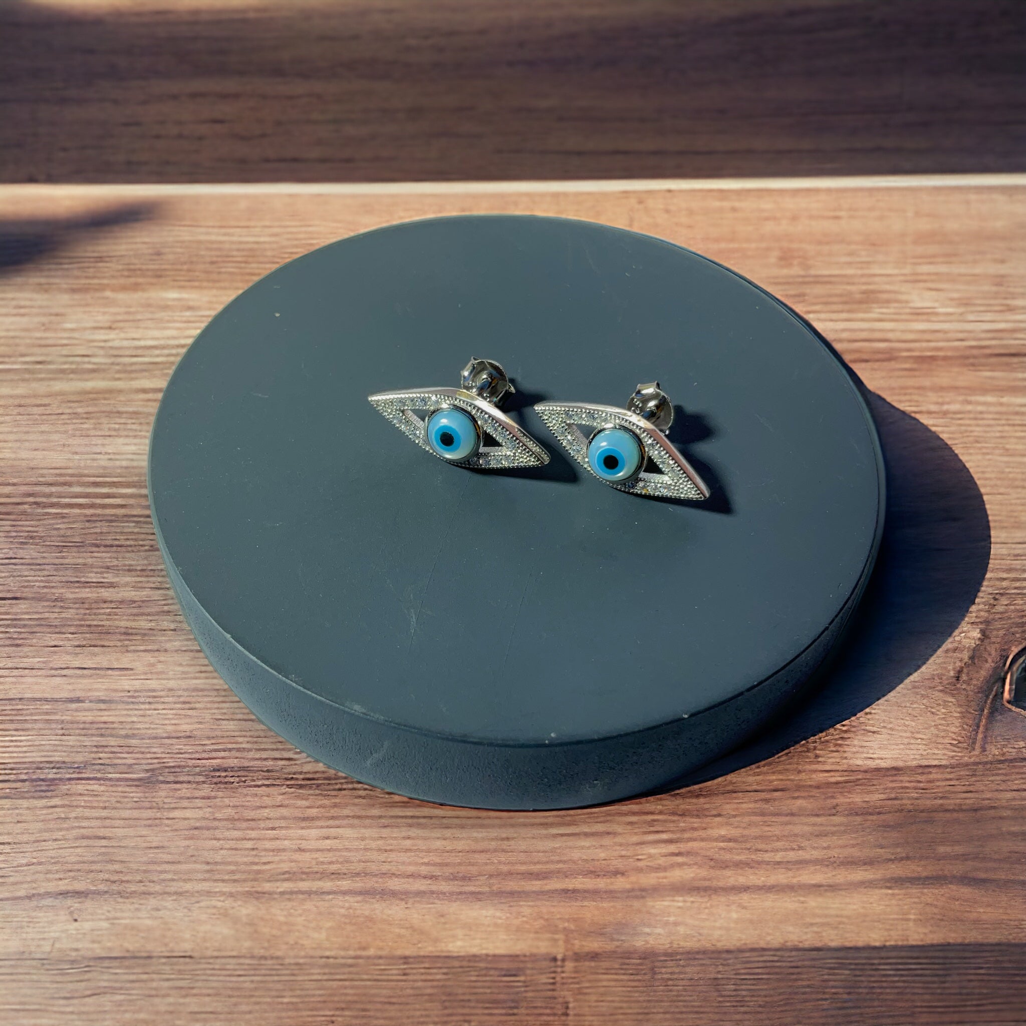 a pair of earrings with blue eyes on a wooden surface