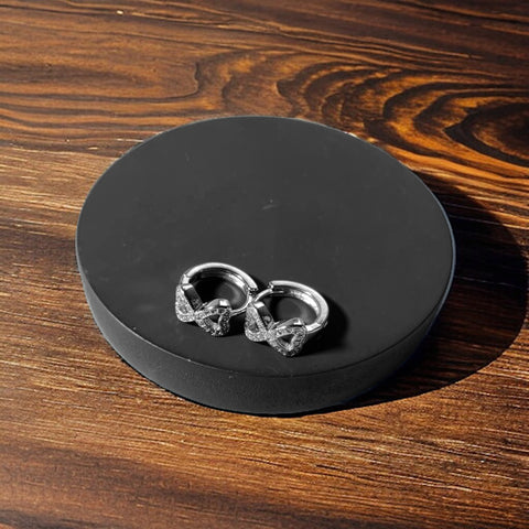 a pair of silver earrings sitting on top of a wooden table