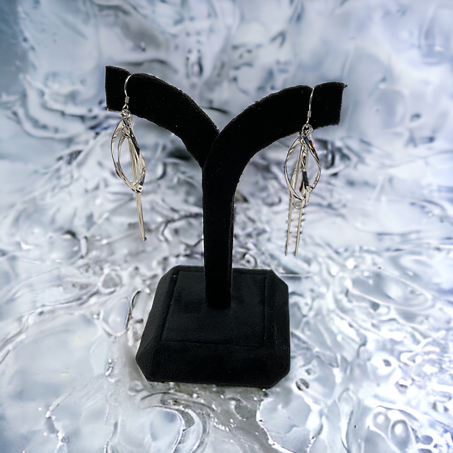 a pair of silver earrings on a black stand