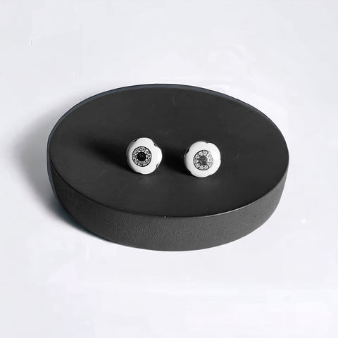a pair of white and black earrings on a black stand