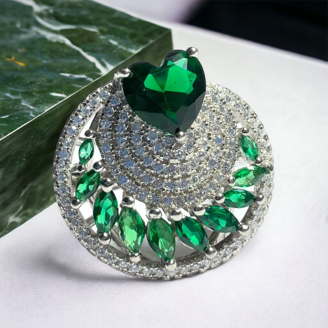 a green heart brooch sitting on top of a table