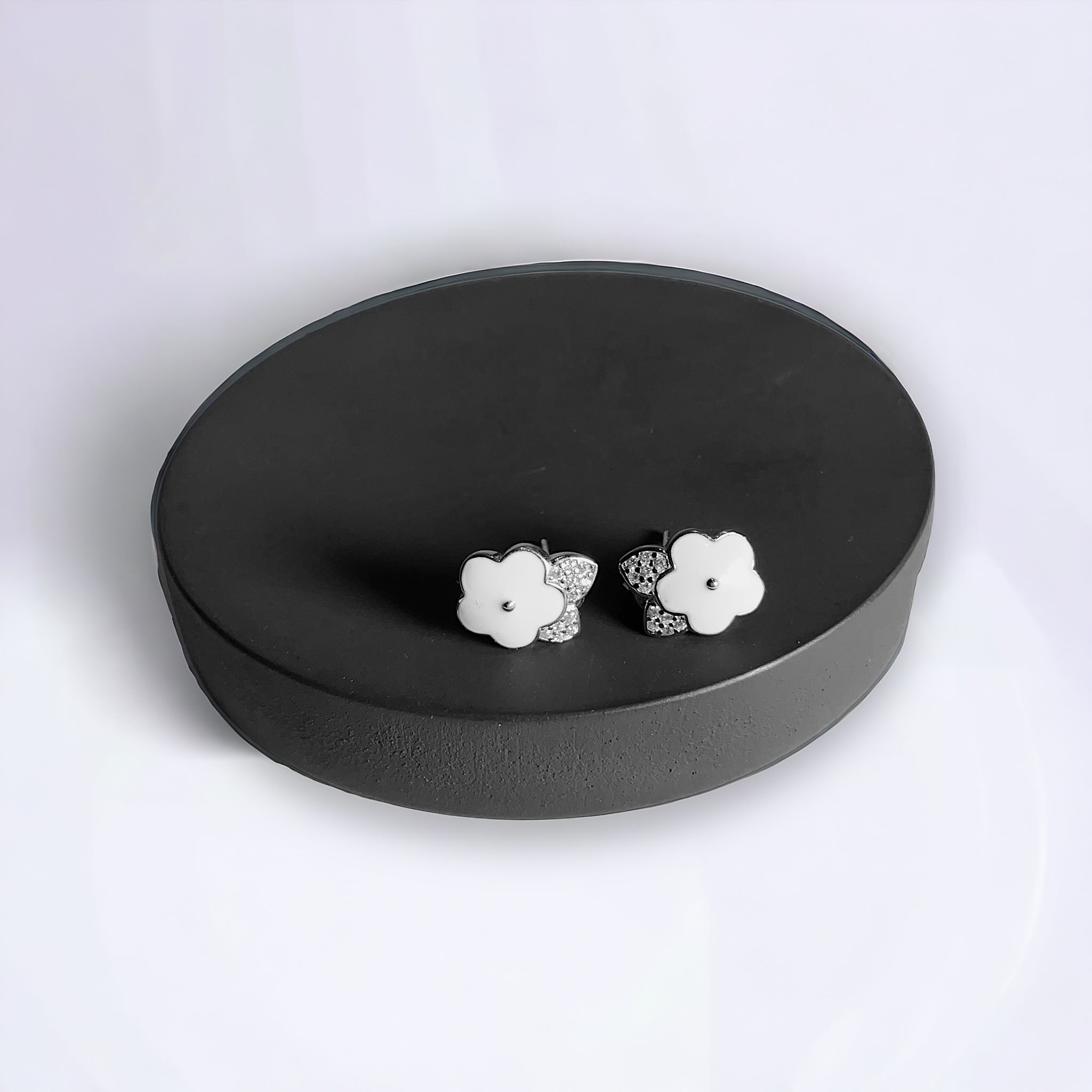 a pair of white flower earrings sitting on top of a black box
