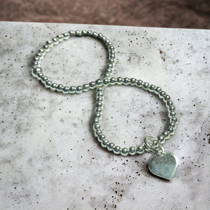 a silver beaded bracelet with a heart charm