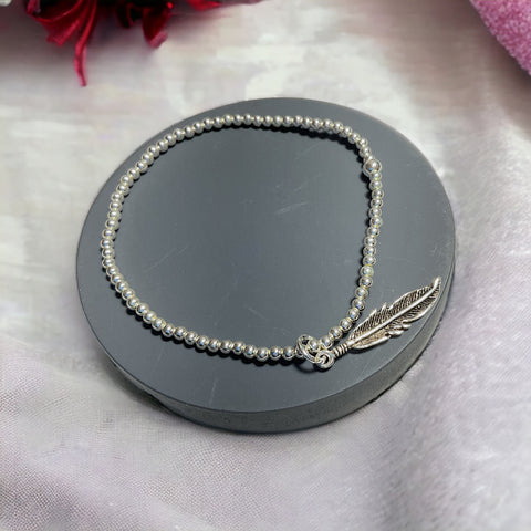 a bracelet with a feather charm on it