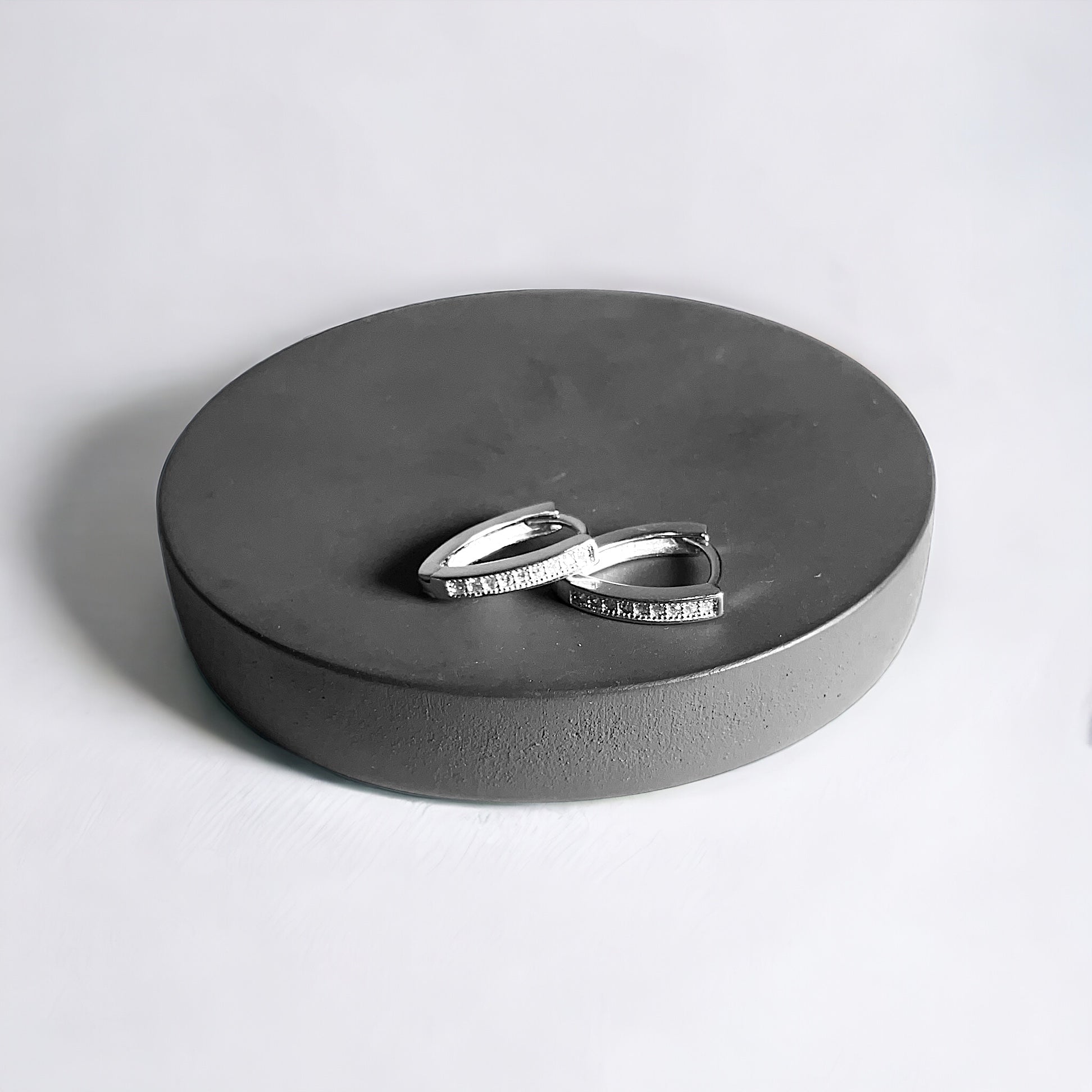 a couple of silver rings sitting on top of a round box
