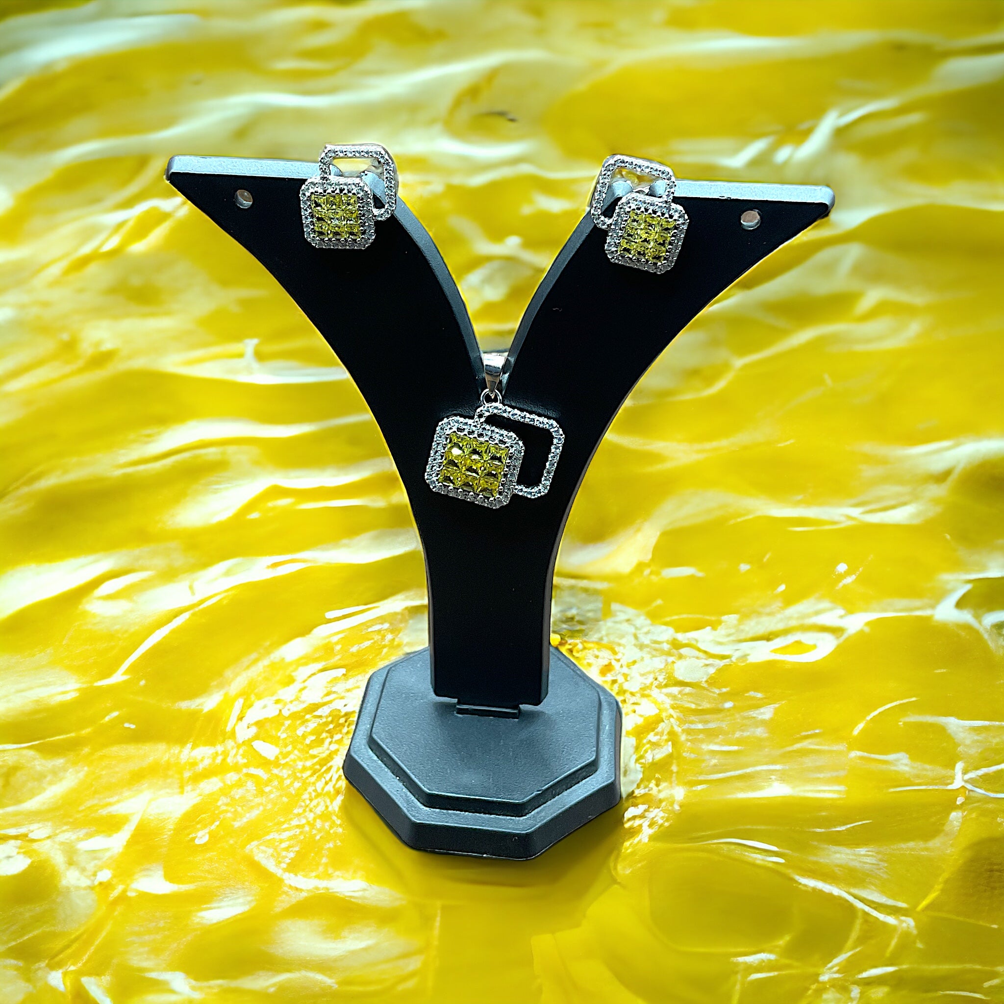 a pair of black and silver earrings sitting on top of a yellow surface