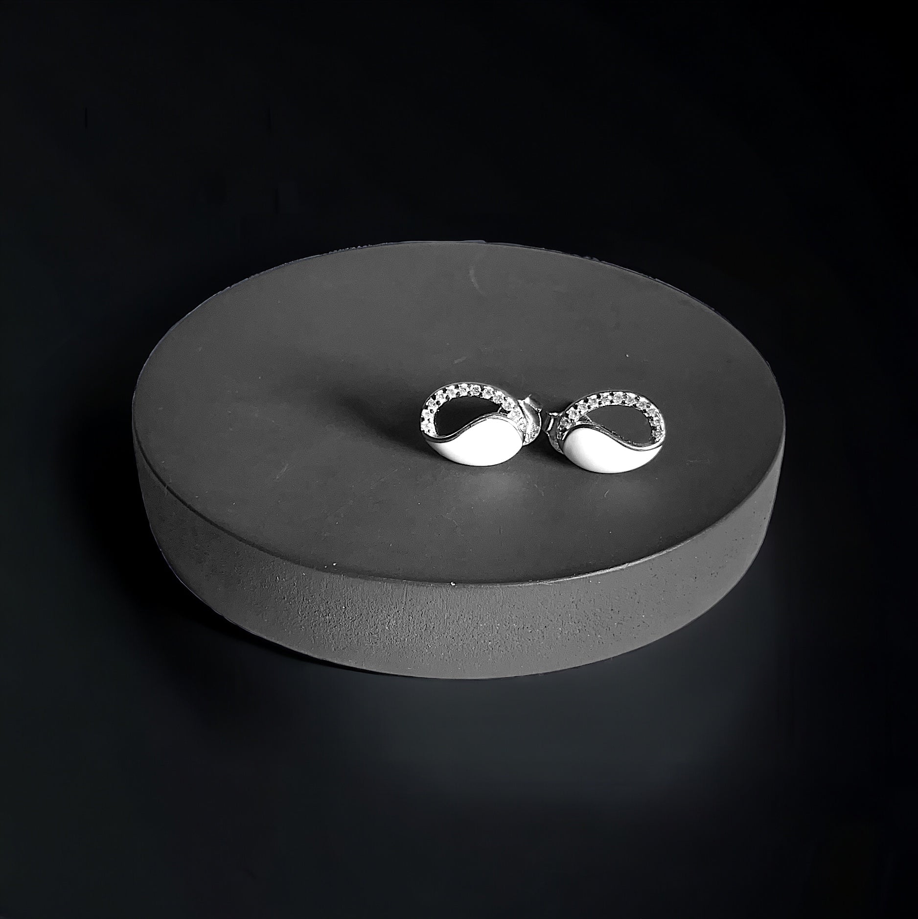 a pair of silver earrings sitting on top of a black surface