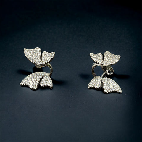 a pair of earrings with white diamonds on a black background