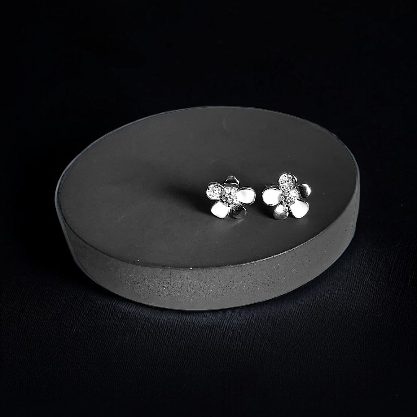 a pair of silver flower earrings on a black background