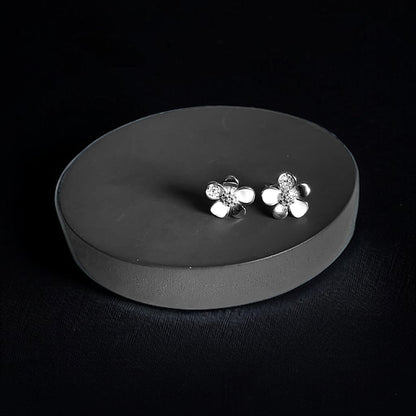 a pair of silver flower earrings on a black background